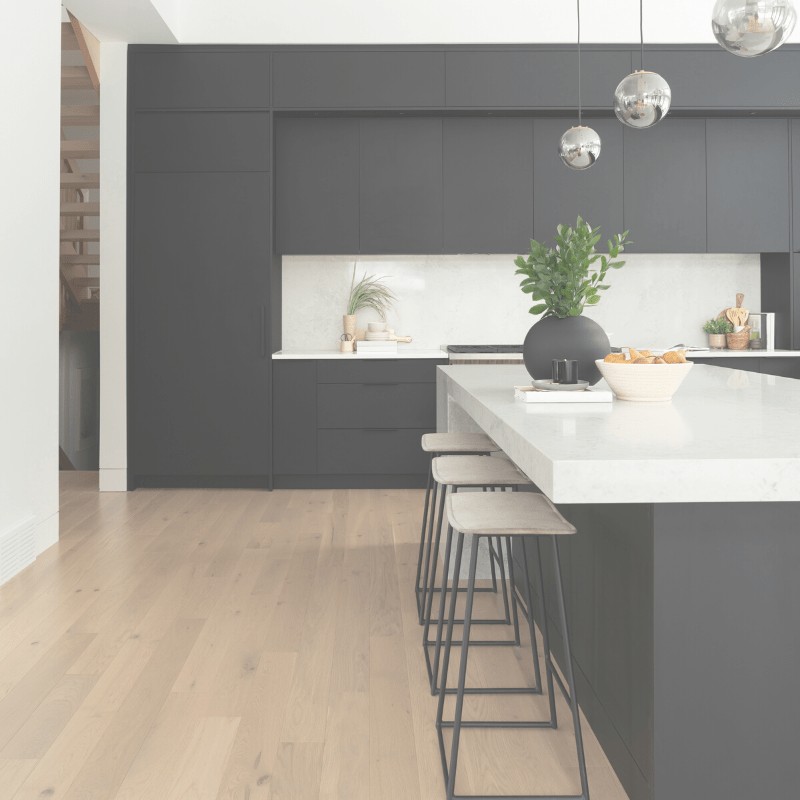 A minimalist kitchen with black cabinets, bar stools, and decorative items on the counter.
