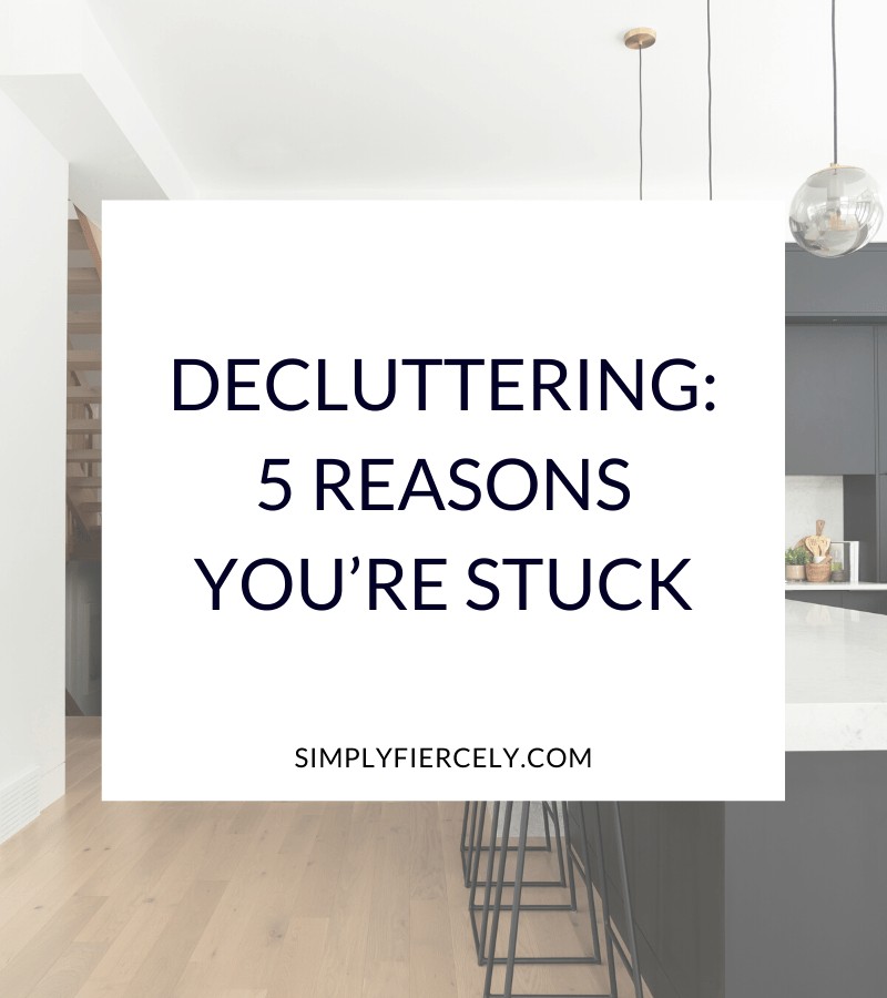"Why Decluttering: 5 Reasons You’re Stuck" in a white box with black kitchen cabinets and bar stools in the background.