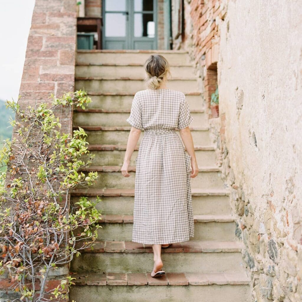A woman walking up a rustic outdoor staircase.