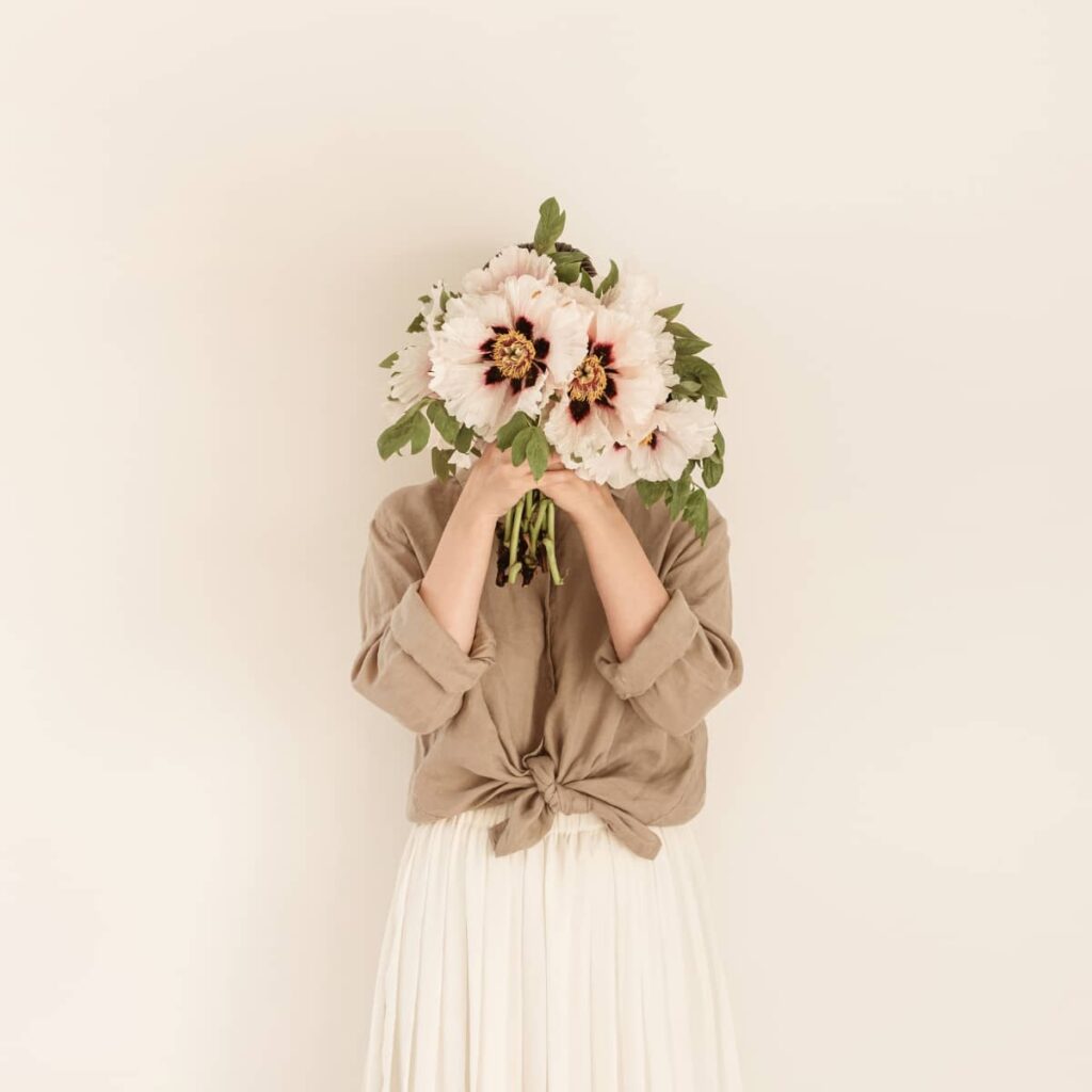 A woman holding a large flower bouquet in front of her face