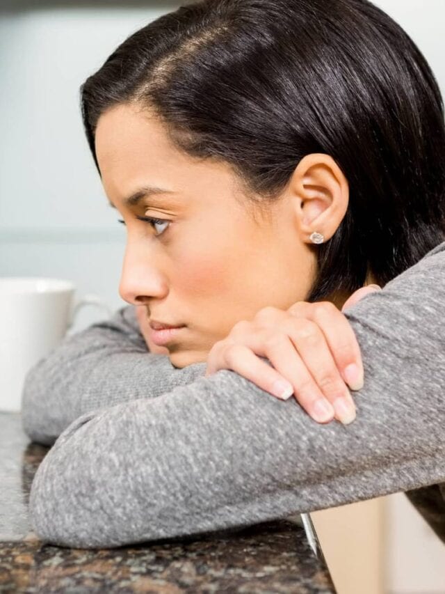 A sad looking lady leaning on the table in front of a laptop