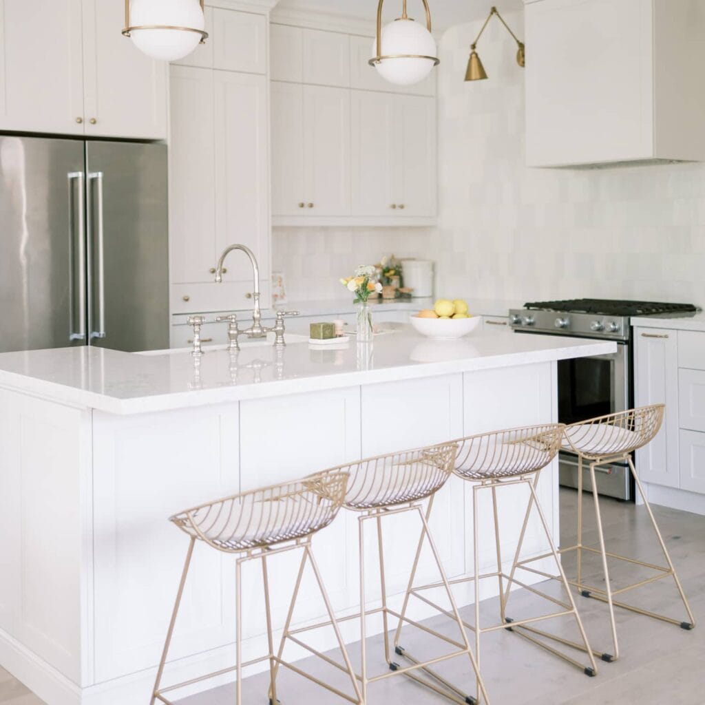 A white minimalist kitchen with gold bar stools.