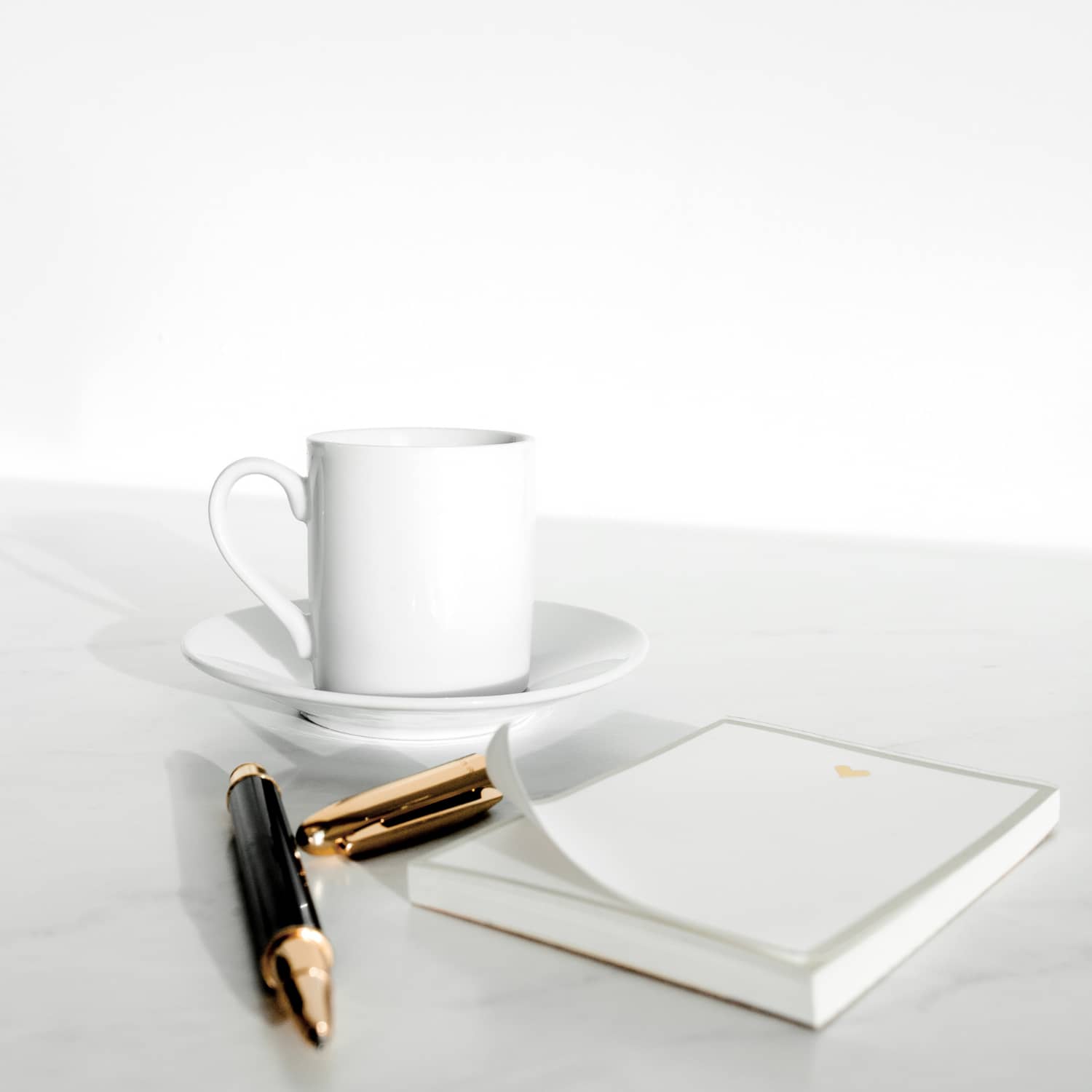 A coffee cup, note pad, and pen in the background.