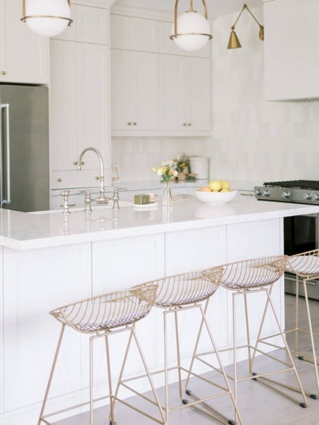 A white minimalist kitchen with gold bar stools.