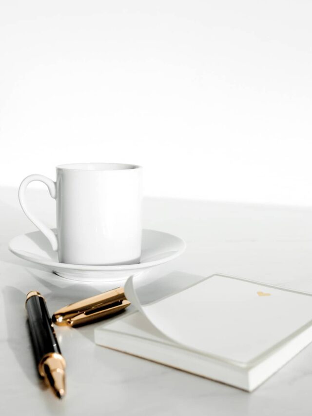 A coffee cup, note pad, and pen in the background.