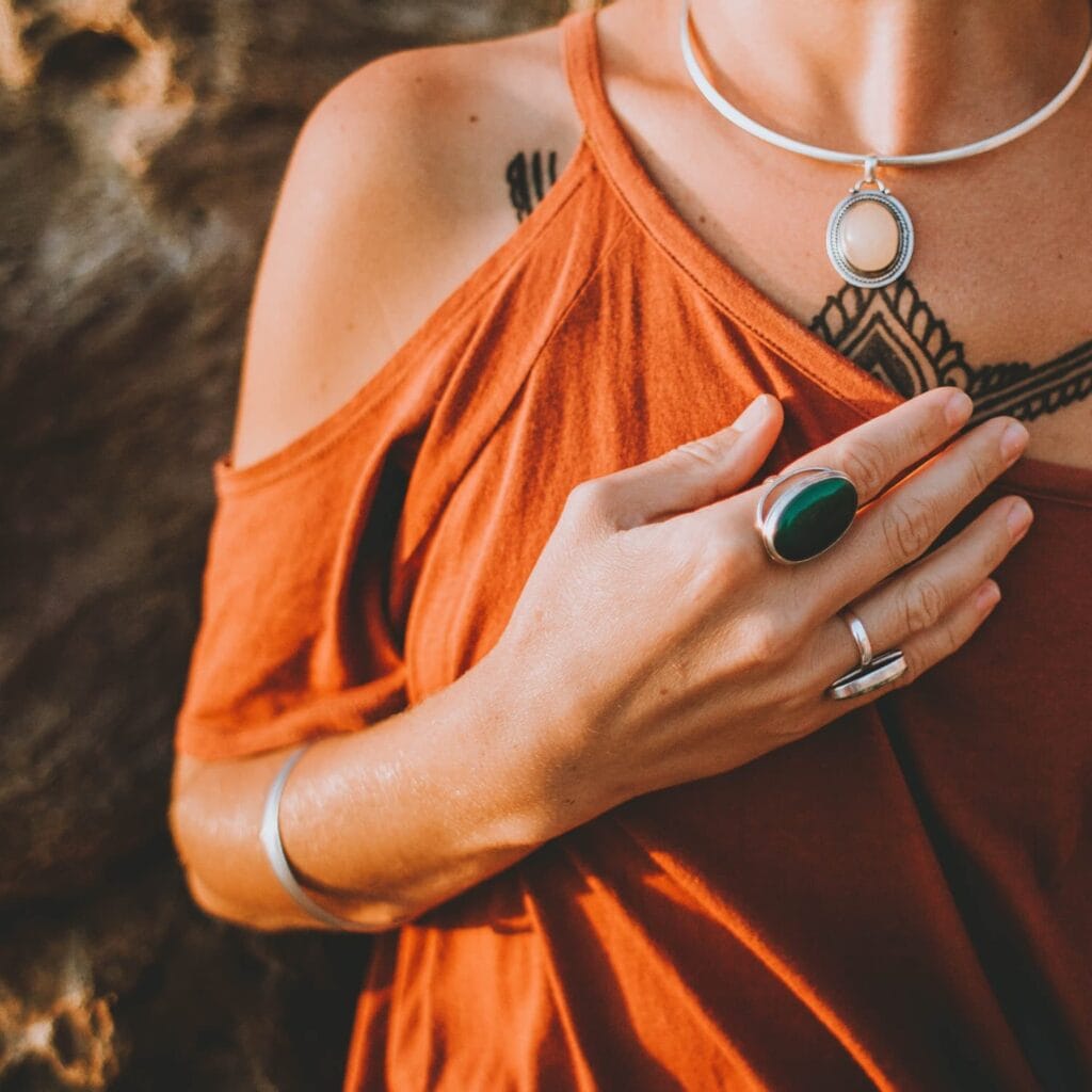 woman wearing a boho orange dress with her hand on her chest