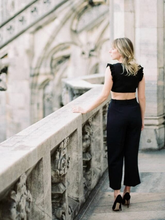 A woman wearing all black walking along a balcony in the background.