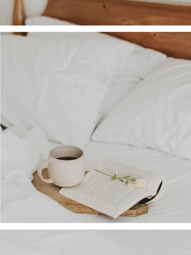 A white square overlay with an image of a wooden tray holding an open book, a small bundle of daisies, and a cup of coffee on top of a bed with a wooden headboard and white linens in the background.