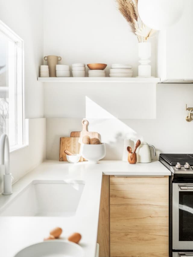 a minimalist kitchen with white countertops, neutral accessories, and lots of natural light