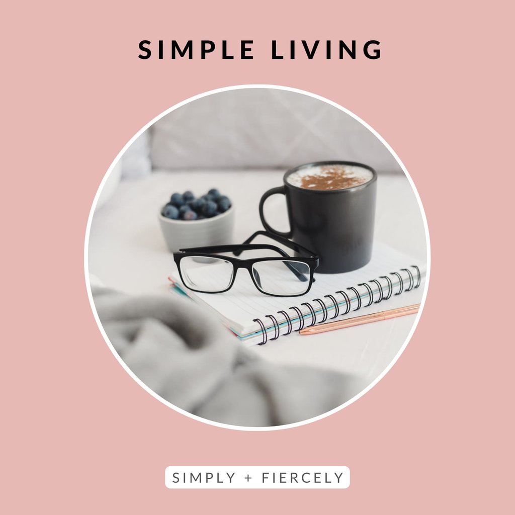 A circular image of notebook with a mug of coffee, reading glasses, and bowl blueberries on top on a pink background with the words simple living across the top.