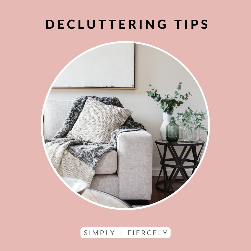 A circular image of a beige sofa with throw pillows and blanket and a black side table with a vase of flowers on a pink background with the words Decluttering Tips across the top