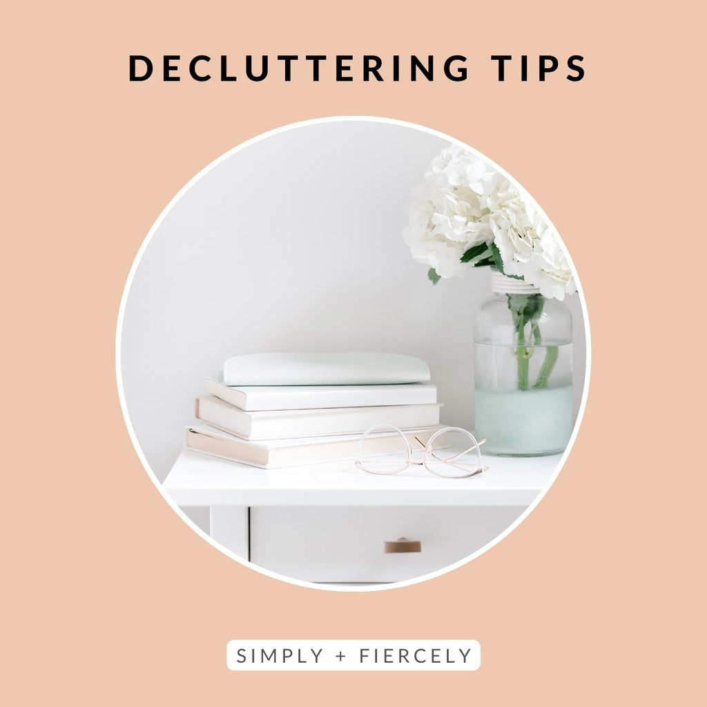 Decluttering Tips on a peachy background with a round image of a white nightstand with a stack of pastel books, a pair of reading glasses, and a vase of white peonies on top.