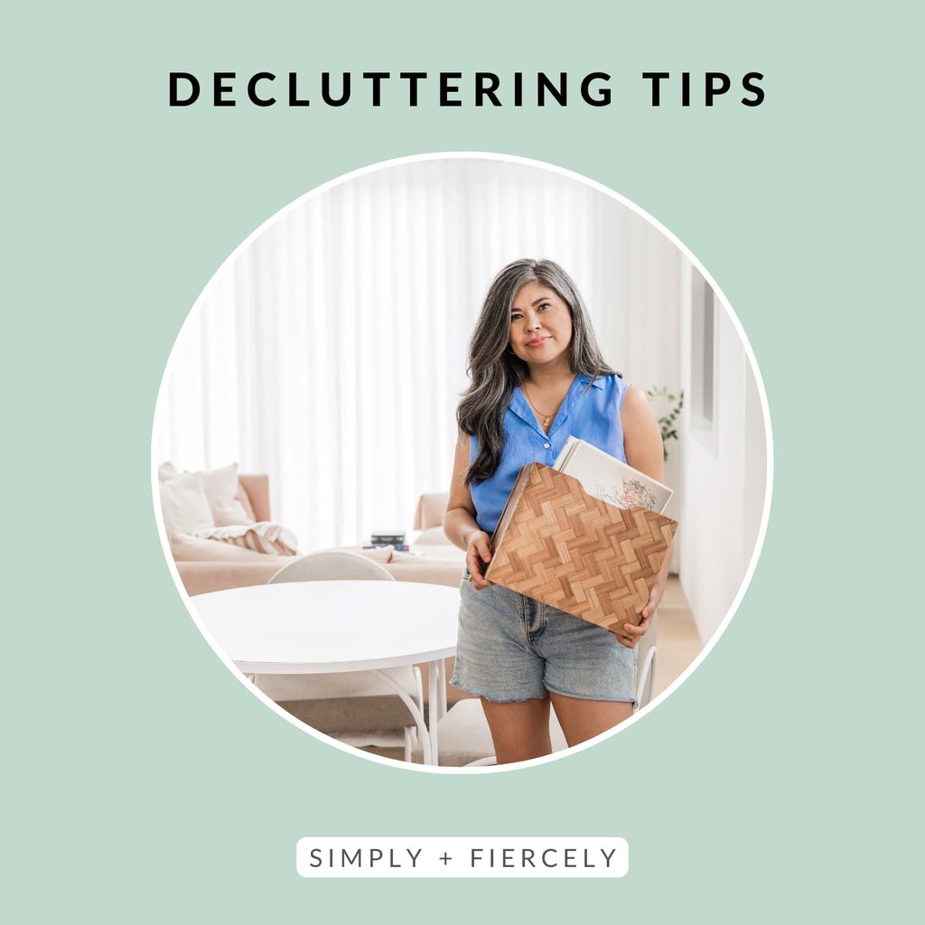 A round image of a woman earing denim shorts and a blue sleeveless top holding a basked of books on a green background with the words Decluttering Tips across the top.