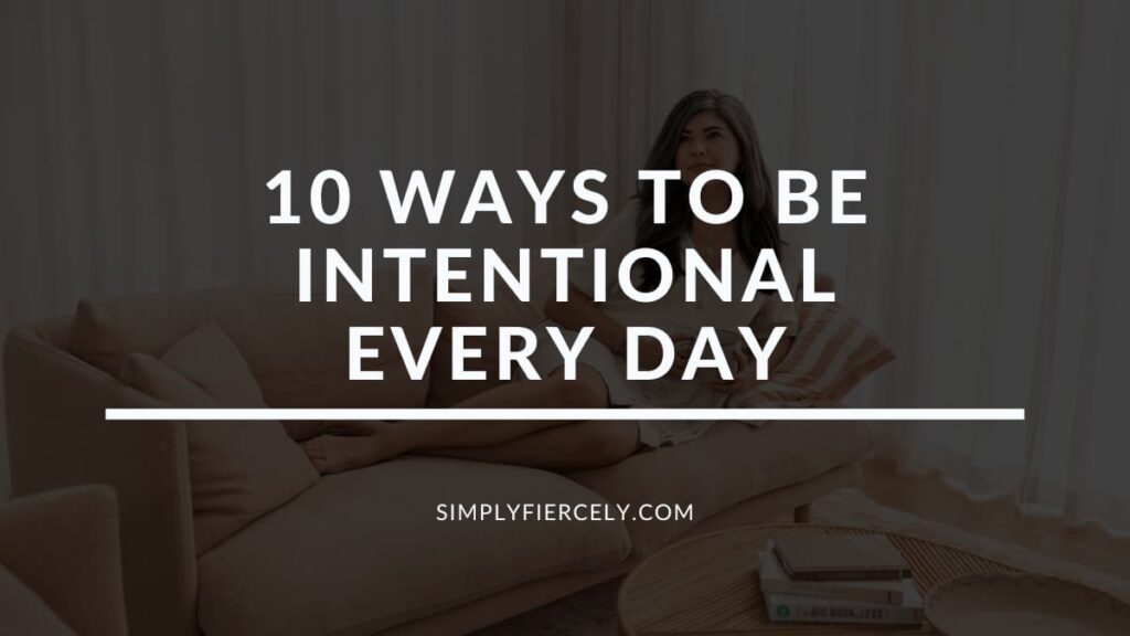 "10 Ways To Be Intentional Every Day" in white letters on a black translucent overlay on top of an image of a woman wearing a dress is holding a coffee cup and lounging on a sofa