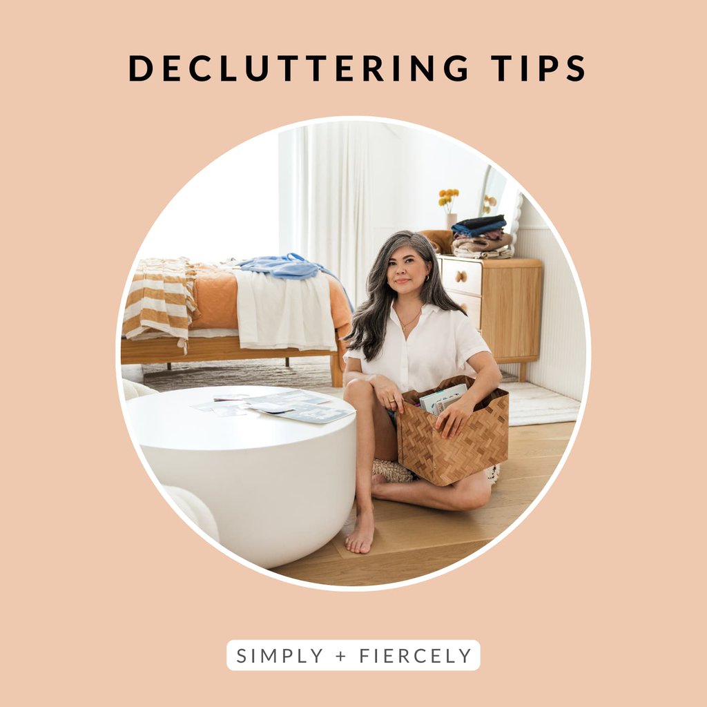 A round image of a smiling woman sitting on the floor holding a basket while decluttering a bedroom on an orange background with the words Decluttering Tips across the top.