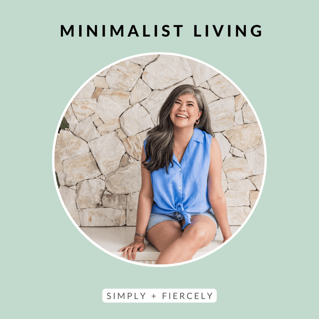 A round image of a smiling woman wearing a blue sleeveless top and denim shorts sitting in front of a stone wall on a green background with the words Minimalist Living across the top.