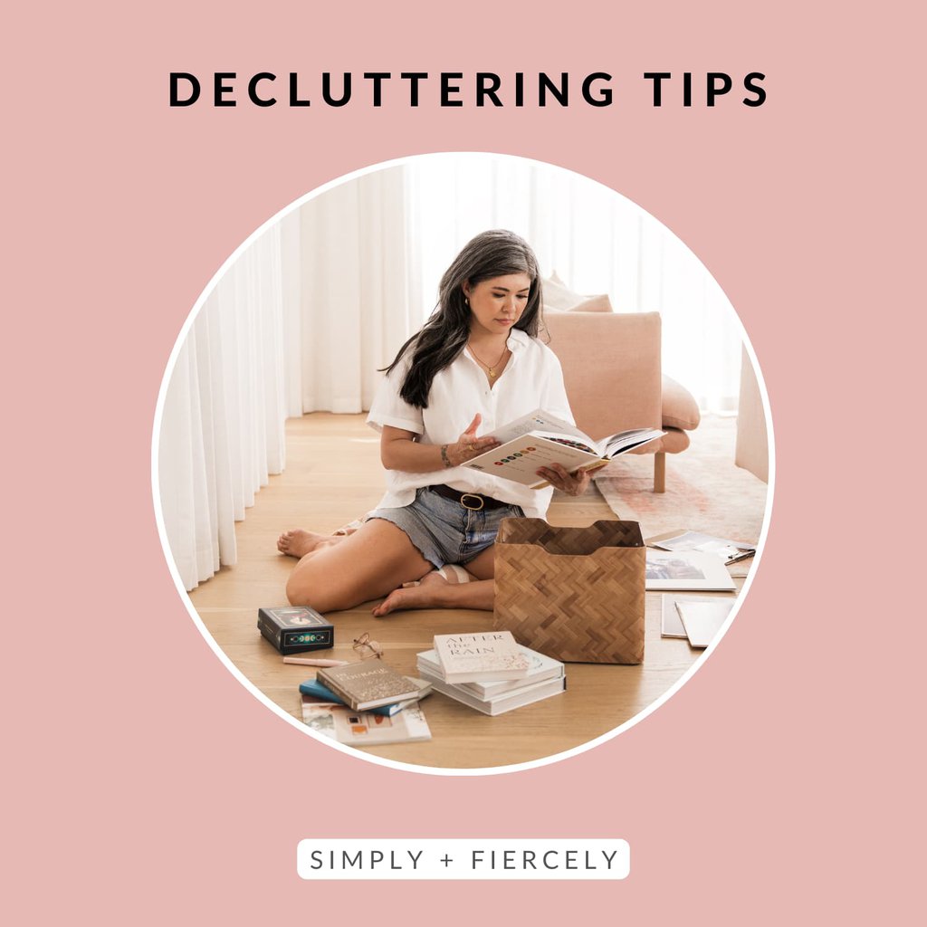 A round image of a woman siting on a hardwood floor decluttering books on a pink background with the words Decluttering Tips across the top.