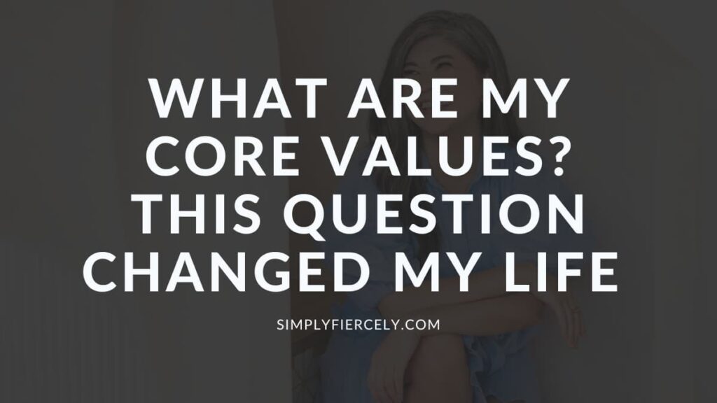 "What Are My Core Values This Question Changed My Life" in white text on a translucent black overlay on top of an image of a smiling woman wearing a blue dress sitting down.
