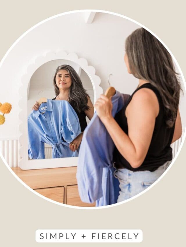 A round image of a smiling woman wearing a sleeveless black top and denim shorts holding a blue dress up to her while looking it the mirror on a beige background with the words Intentional Living across the top.