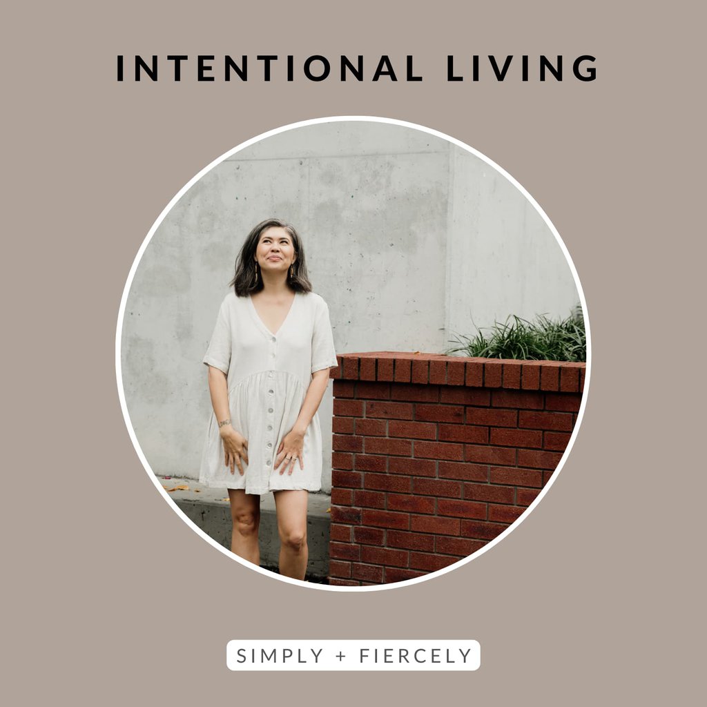 A round image of a smiling woman wearing white dress standing next to a short brick wall looking up at the sky on a taupe background with the words Intentional Living across the top.