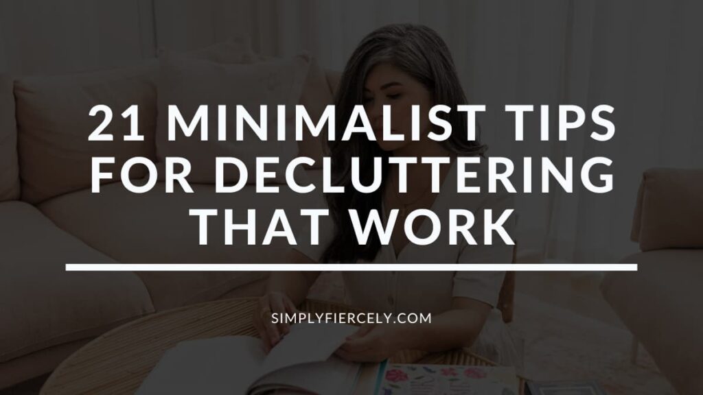 "21 Minimalist Tips For Decluttering That Work" in white letters on a translucent black background on top of an image of a woman sitting at a table on the floor in front of a sofa decluttering books.