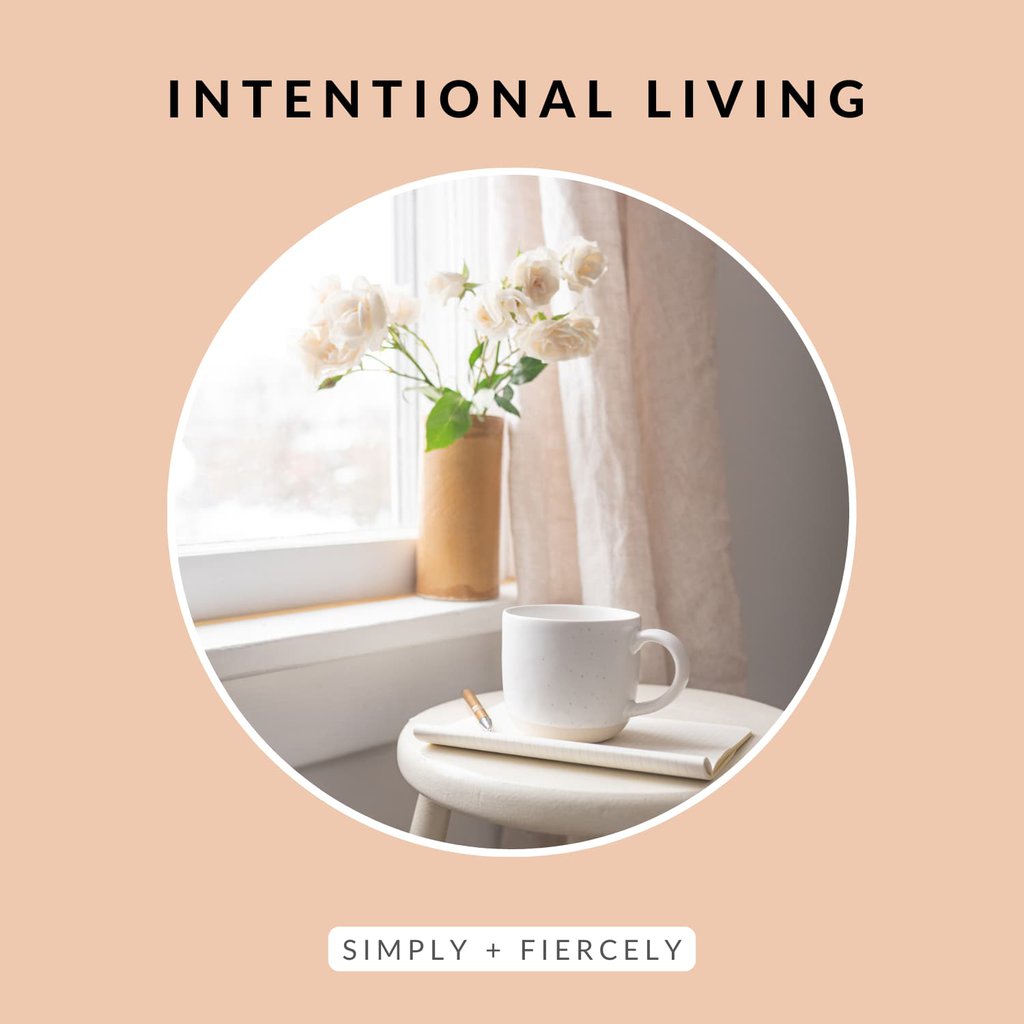 A round image of a wooden stool in front of a window with a book and coffee mug on top with a flower vase on the window sill on an orange background with the words Intentional Living across the top.