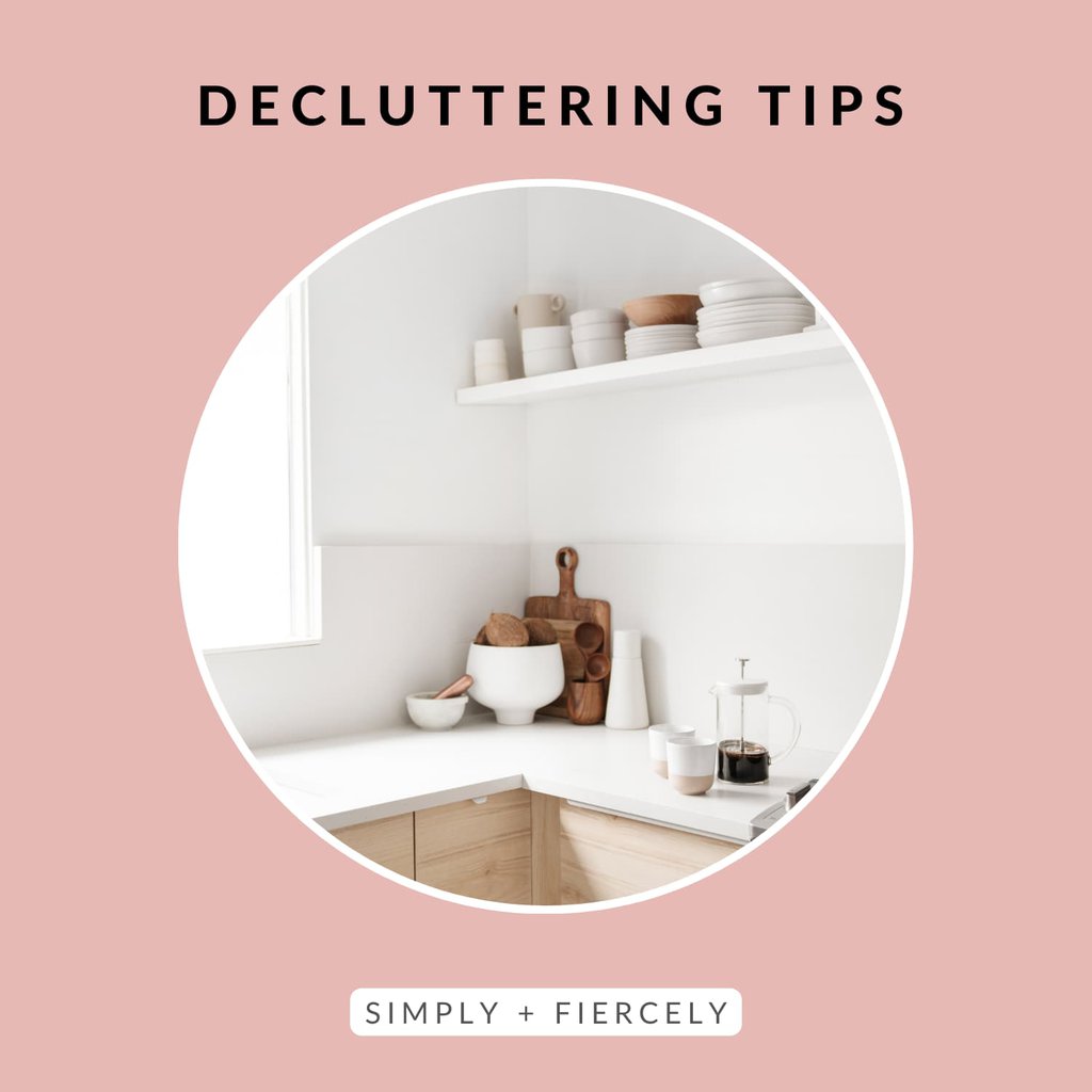 A round image of a kitchen with a cutting board, white bowl, coffee mugs and a french press on the counter on a pink background with the words Decluttering Tips across the top.