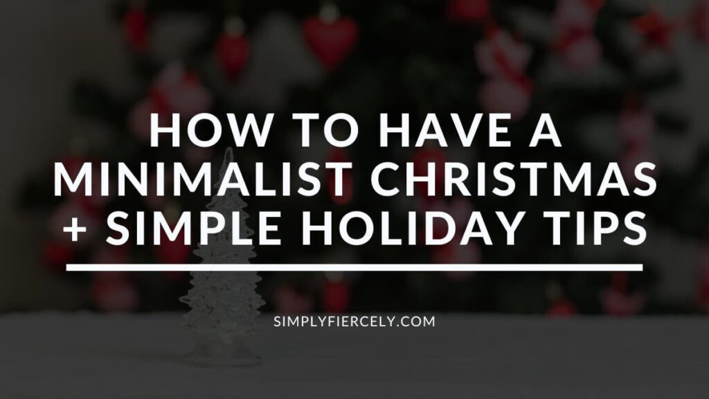 "How To Have A Minimalist Christmas + Simple Holiday Tips" in white letters on a translucent black overlay on an image of a small crystal Christmas tree with a Christmas tree blurred out in the background.