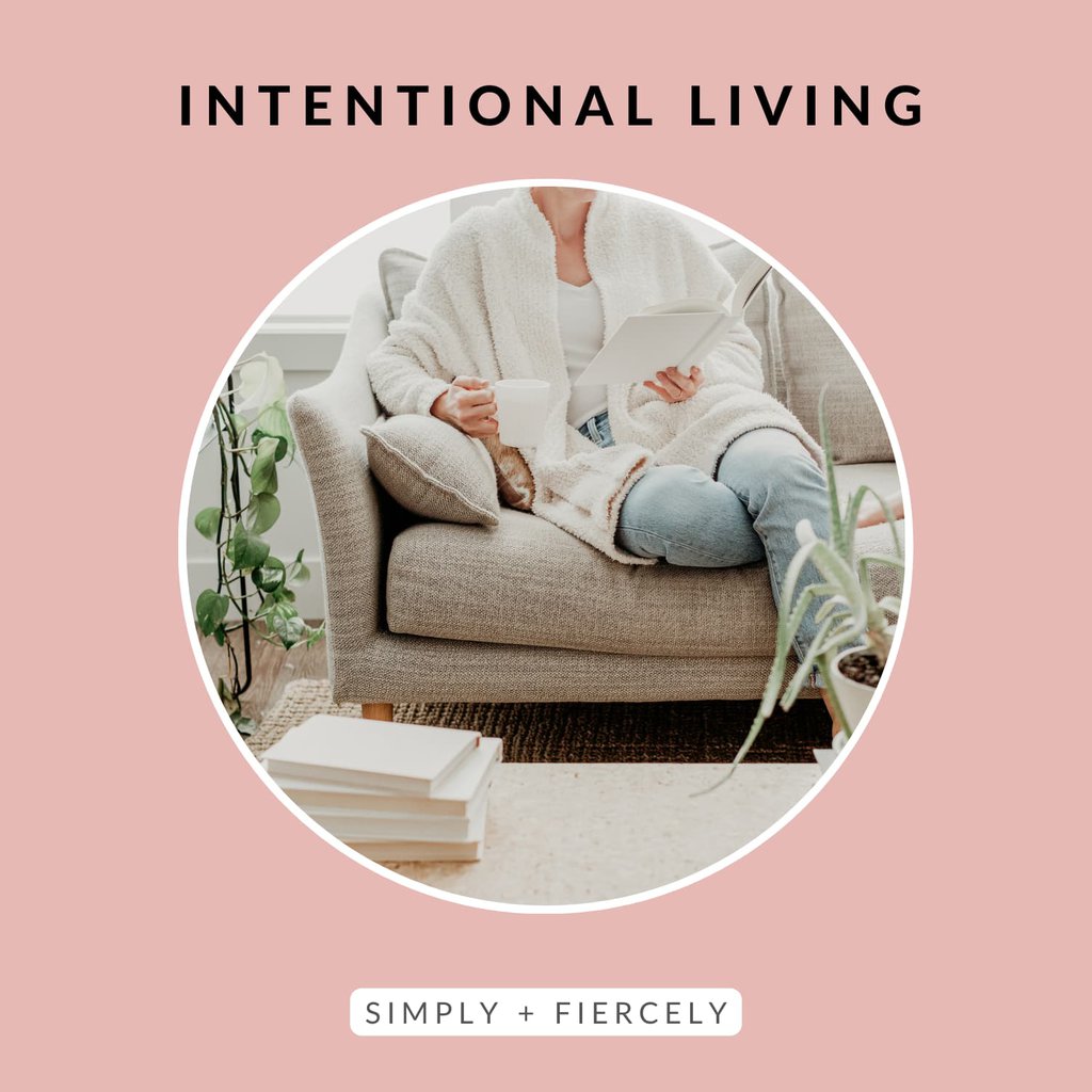A round image of a woman sitting on a beige sofa holding a coffee mug and reading a book on a pink background with the words Intentional Living across the topl