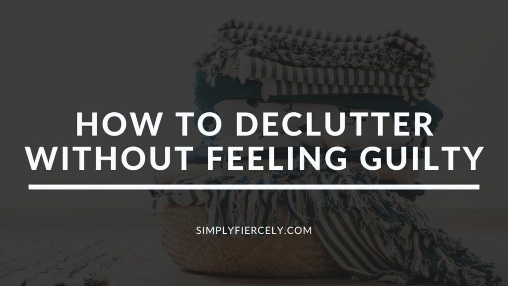 "How to Declutter Without Feeling Guilty" in white letters on a translucent black overlay on an image of a wicker basket full of white, grey and blue striped linens on a white background.