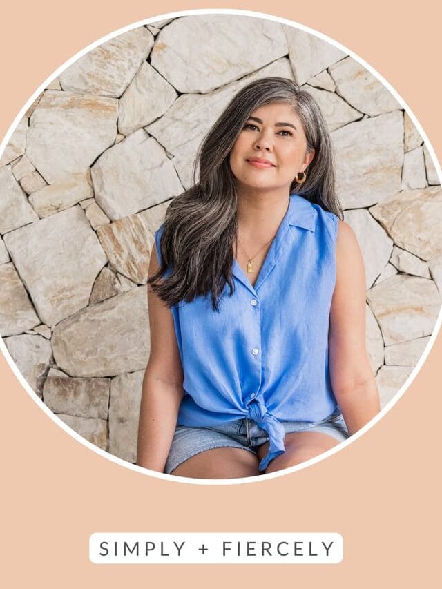 A round image of a smiling woman wearing a blue sleeveless top and shorts sitting in front of a stone background on an orange background with the words Decluttering Tips across the top.